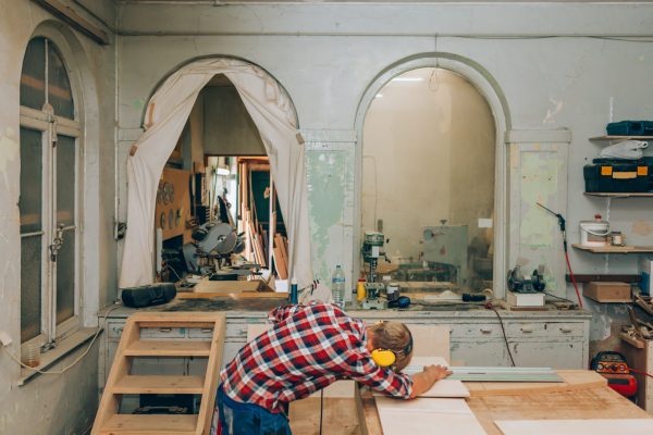 Designer man doing wood carpentry project using mowing saw inside workshop